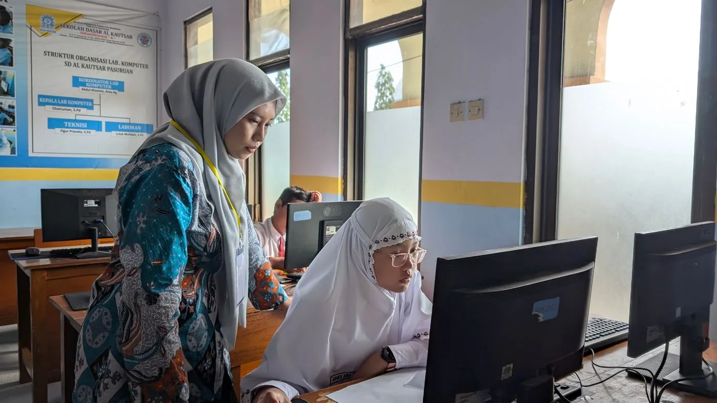 A teacher mentoring a student at the computer lab